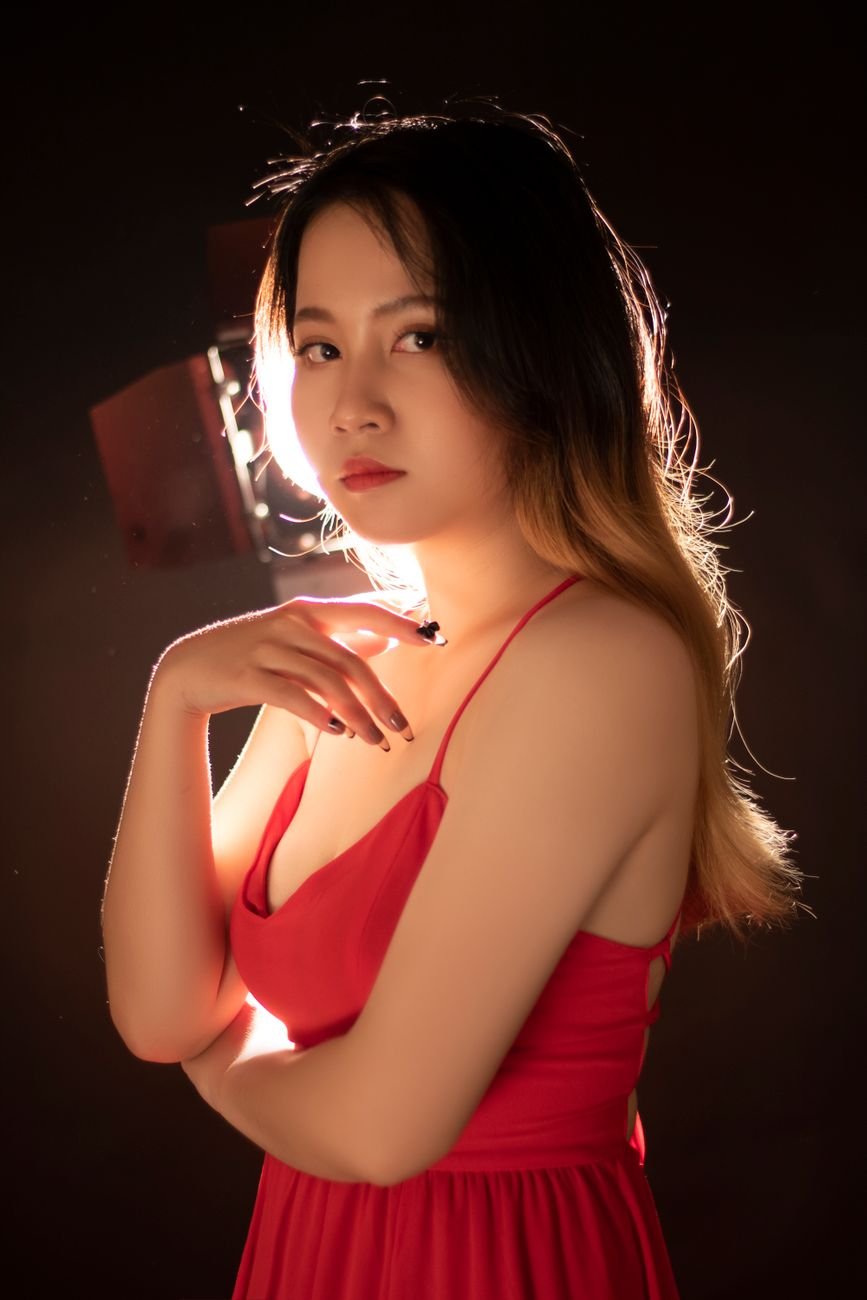 Captivating portrait of a woman in a red dress, highlighted by dramatic studio lighting.
